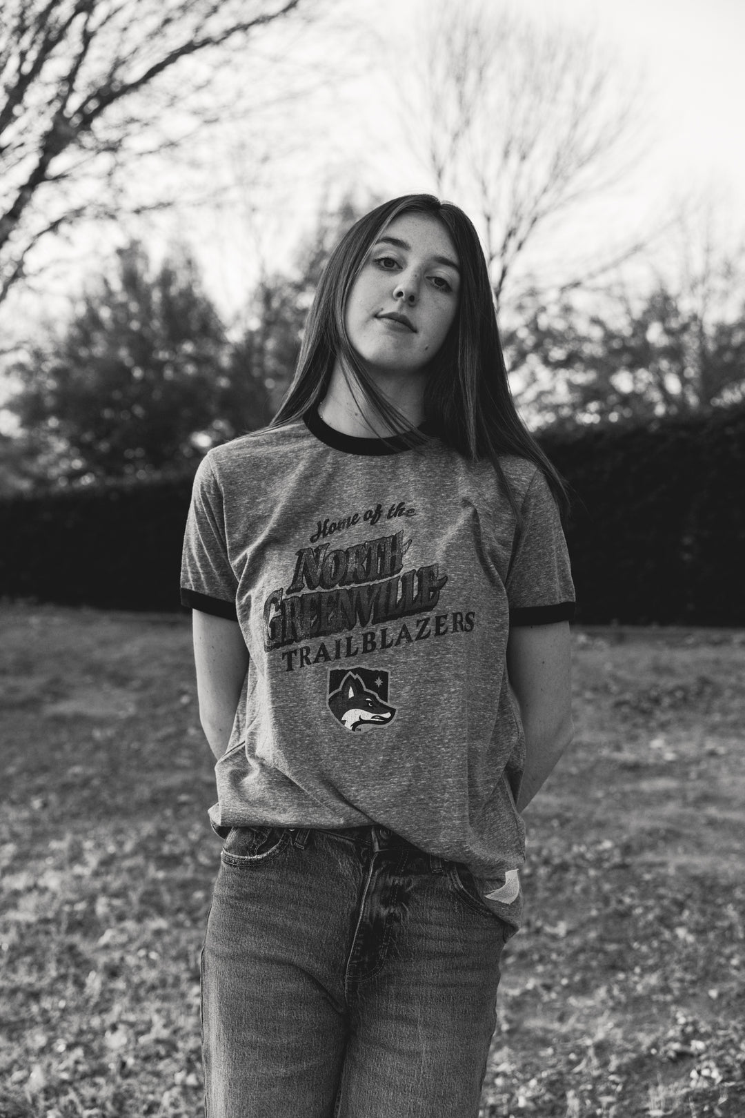 Woman wearing a vintage-style t-shirt with 'Home of the North Greenville Trailblazers' text and graphics outdoors.
