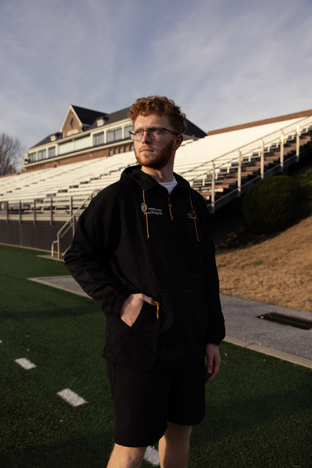 Man standing on a sports field with stadium seats in the background
